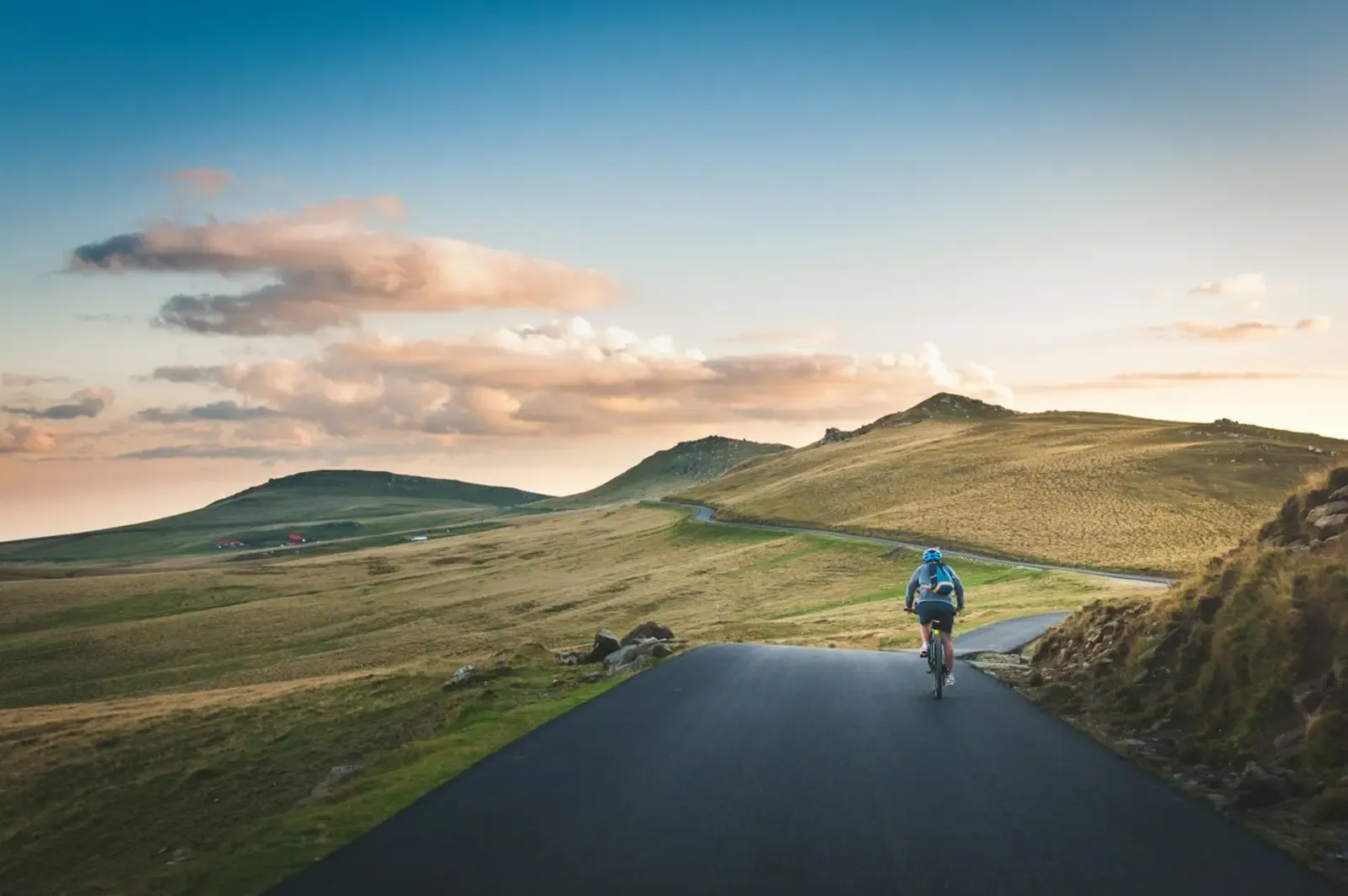 Ciclista pedalando em uma estrada de montanha ao amanhecer